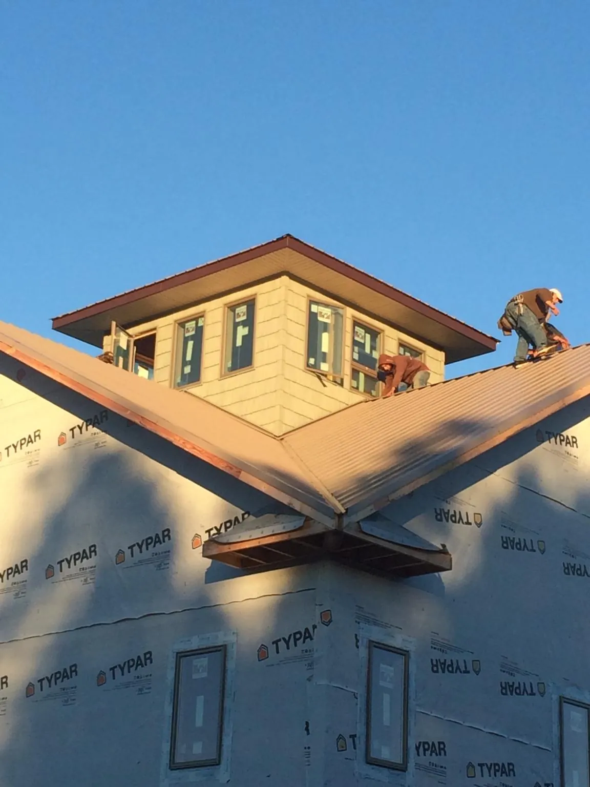 Roofers working around a rooftop cupola on a new metal roof at sunset — Roof Waterproofing in Clermont by Roofing Brothers